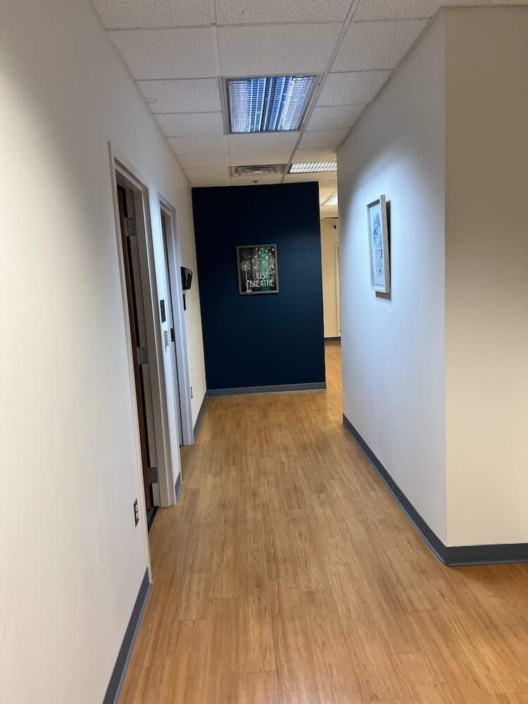 Blueview Recovery hallway with wood flooring, white walls, and framed artwork.