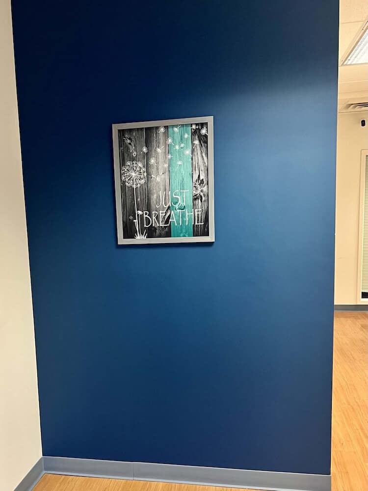 Blueview Recovery hallway with blue accent wall and “Just Breathe” artwork.