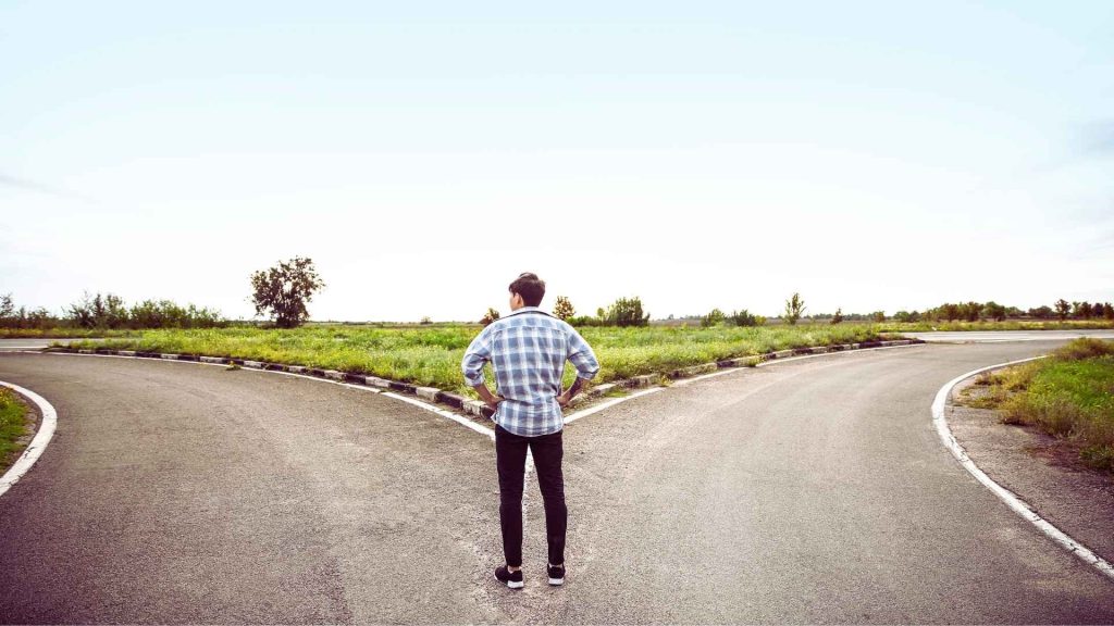 Person standing at a fork in the road, representing choices related to cocaine addiction and recovery
