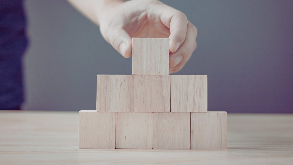 Hand stacking wooden blocks to represent building a personalized relapse prevention plan