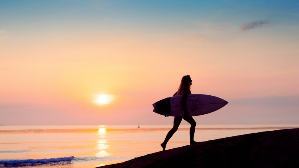 Silhouette of a surfer at sunrise, representing urge surfing as a relapse prevention technique for managing cravings.