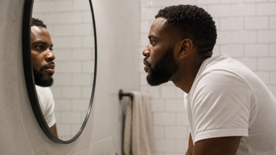Bipolar Disorder vs. Borderline Personality Disorder hero image of a man staring at himself in a mirror.
