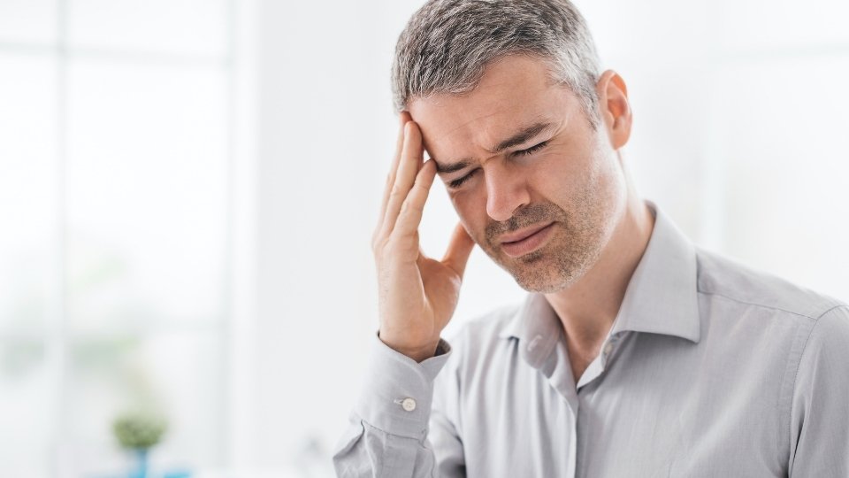 a man holds his head after experiencing alcohol dementia.